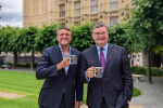 Ben and Iain holding MK's Best Cafe mugs outside the Houses Of Parliament