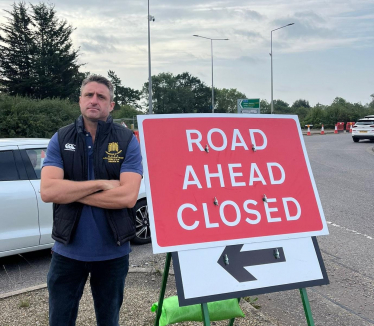 Ben Everitt MP standing next to the 'Road Ahead Closed' sign by the A509 at Newport Pagnell